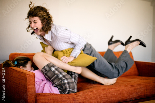 Mid-adult business woman playing with her teenage daughter on a couch.