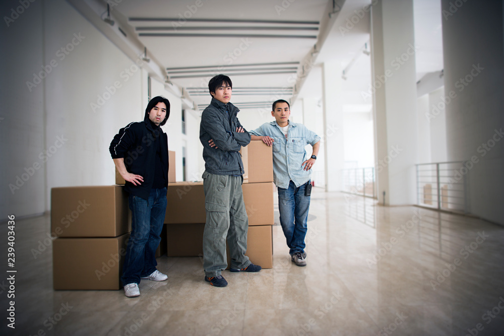 Portrait of three young men standing inside a large empty room. Portrait of three young men standing inside a large empty room.