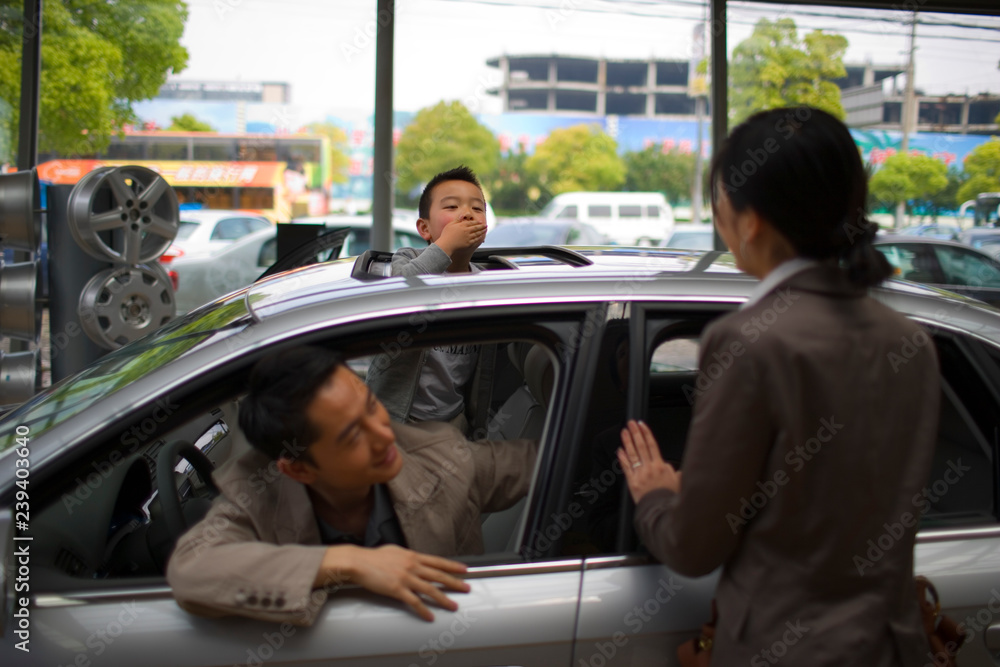 Young boy blowing his mother a kiss through the sunroof of a car inside a car showroom. Young boy blowing his mother a kiss through the sunroof of a car inside a car showroom.