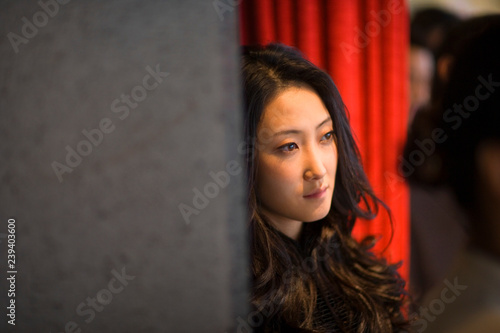 Young adult business woman leaning against a wall.