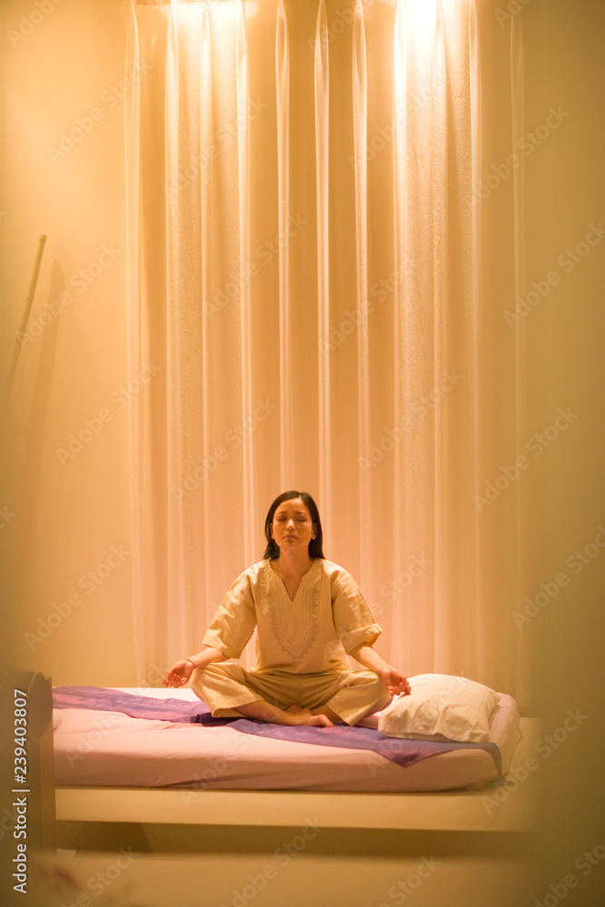 Woman meditating in a Zen-like room. Woman meditating in a Zen-like room.