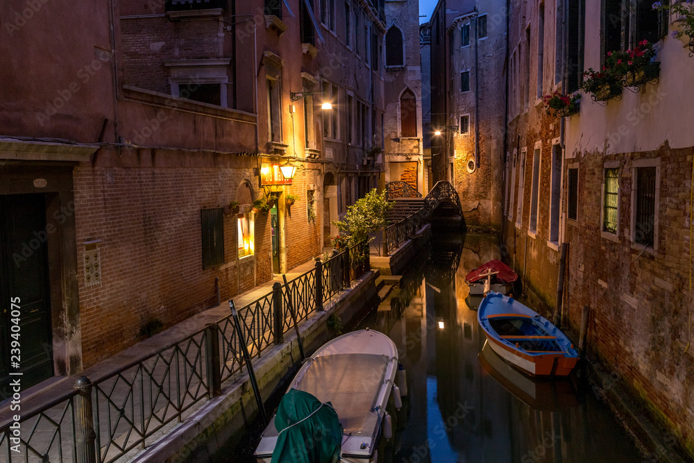 Venice canal at late night time with street light illuminating bridge and houses
