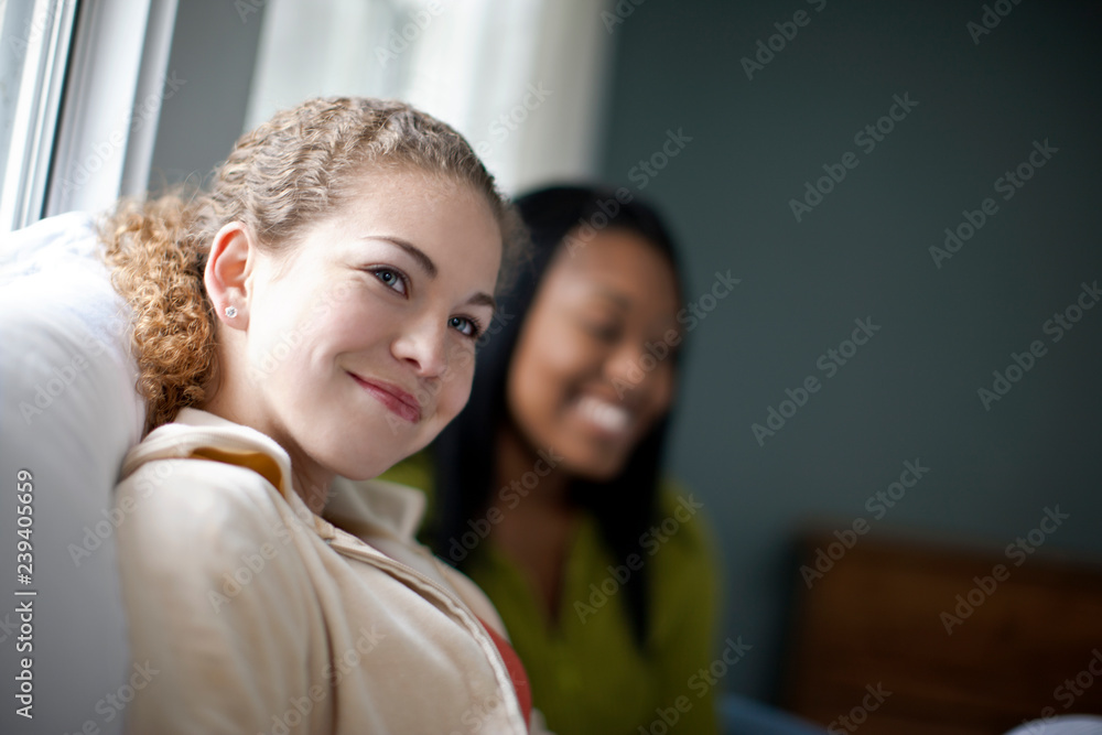 Smiling friends sitting on bed at home Smiling friends sitting on bed at home