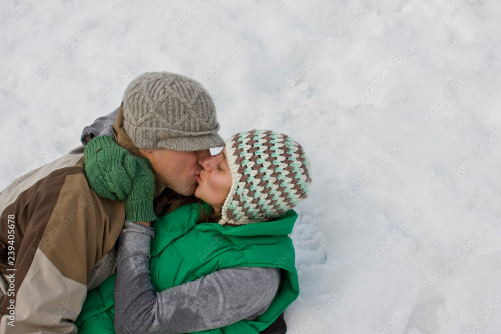 Young couple kissing while lying in the snow. Young couple kissing while lying in the snow.