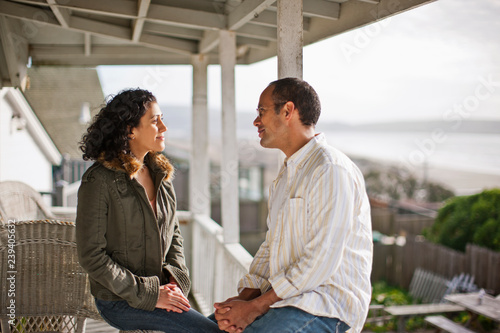 Happy young couple talking on a verandah.