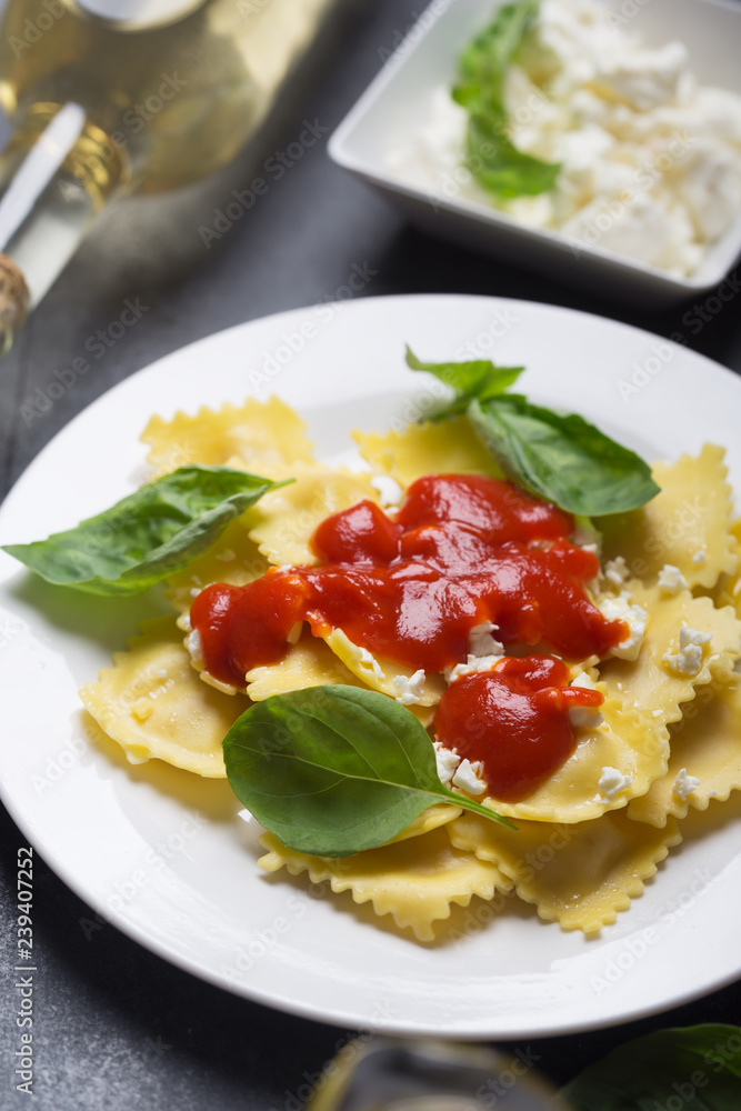 Boiled ravioli with basil, cheese and tomato sauce on a black background Boiled ravioli with basil, cheese and tomato sauce on a black background