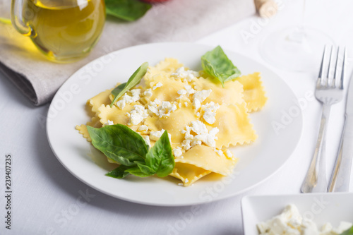 Boiled ravioli with basil, cheese and tomatoes on white table