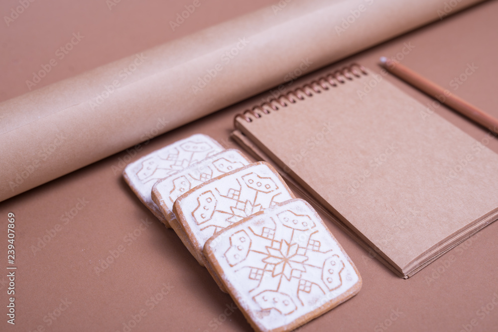 A blank notebook with Christmas cookies and wrapping paper on table, close up A blank notebook with Christmas cookies and wrapping paper on table, close up