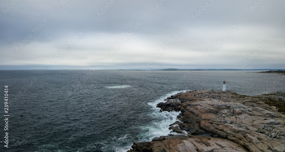 Aerial panoramic view of a Lighthouse on a rocky coast of the Atlantic Ocean. Taken in Peggy Cove, near Halifax, Nova Scotia, Canada.