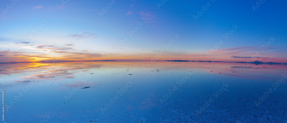 Fototapeta premium Uyuni reflections. One of the most amazing things that a photographer can see. Here we can see how the sunrise over an infinite horizon with the Uyuni salt flats making a wonderful mirror to infinity