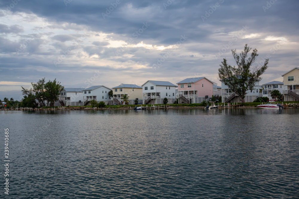 Obraz premium View of residential homes on the ocean shore during a vibrant cloudy sunset. Taken in Key West, Florida Keys, United States.