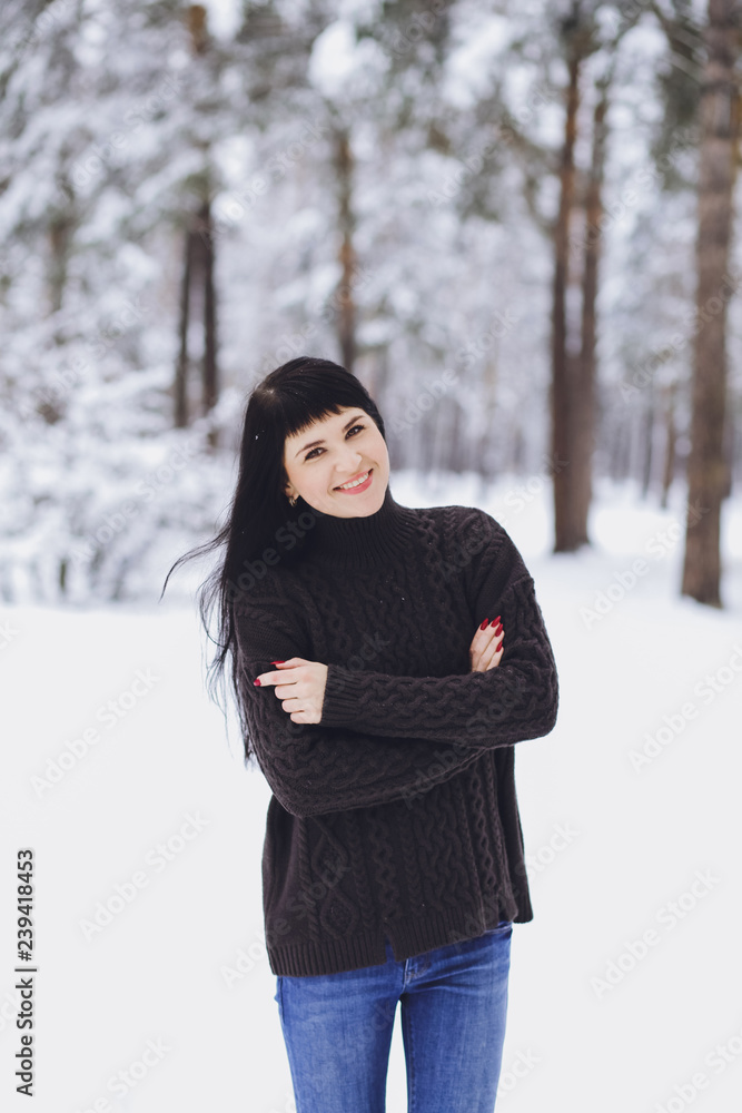 Young beautiful brunette girl in a sweater in the winter snowy forest Young beautiful brunette girl in a sweater in the winter snowy forest