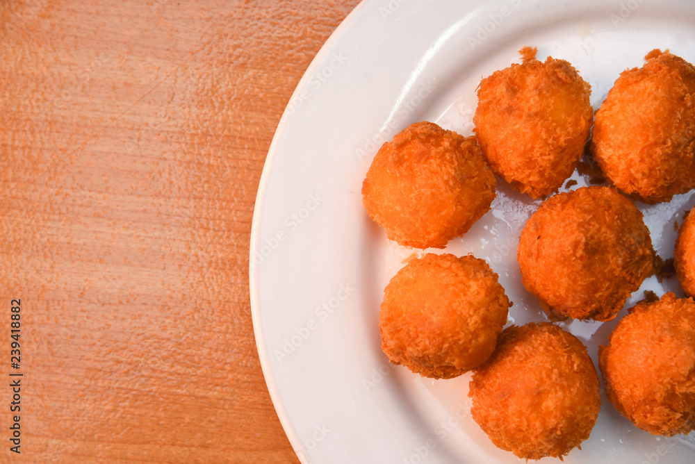Cheese balls, Breaded mozzarella cheese balls with tomato in white dish on wood blackground Cheese balls, Breaded mozzarella cheese balls with tomato in white dish on wood blackground