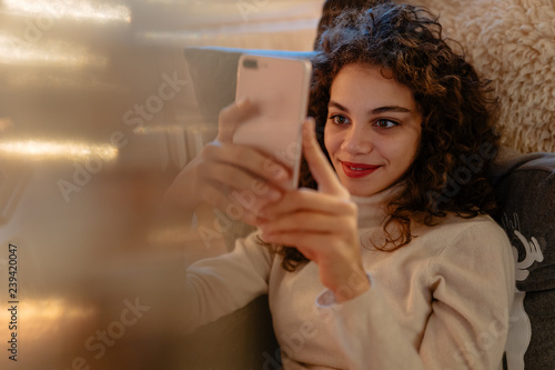 Hübsche lächelnde Frau liest eine Nachricht auf ihrem Smartphone