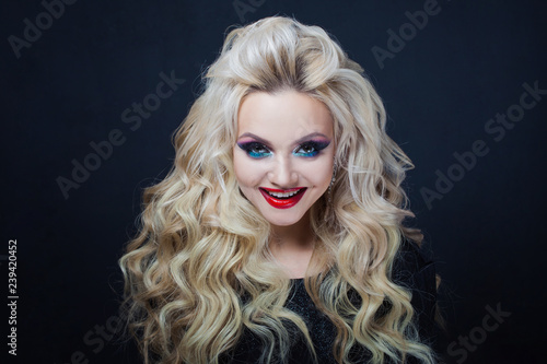 Portrait of smiling young luxurious blonde with long curls.