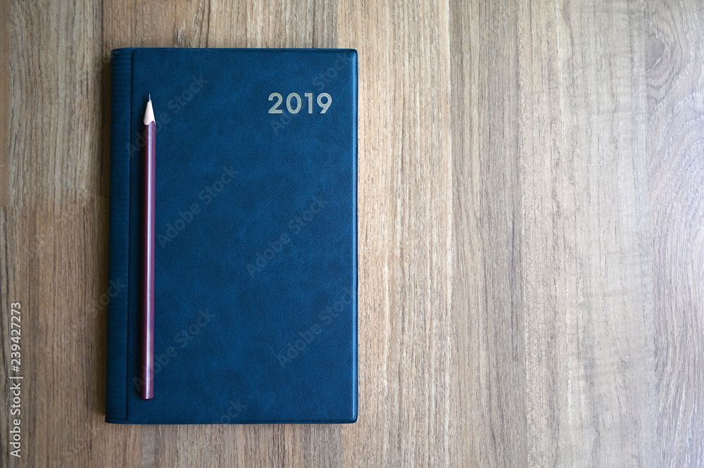 Blue notebook with number 2019 and pencil on wooden table with copy space for text or product display. Blue notebook with number 2019 and pencil on wooden table with copy space for text or product display.