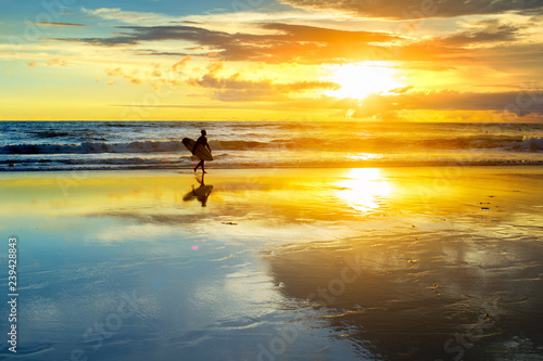 surfer on beach at susnet