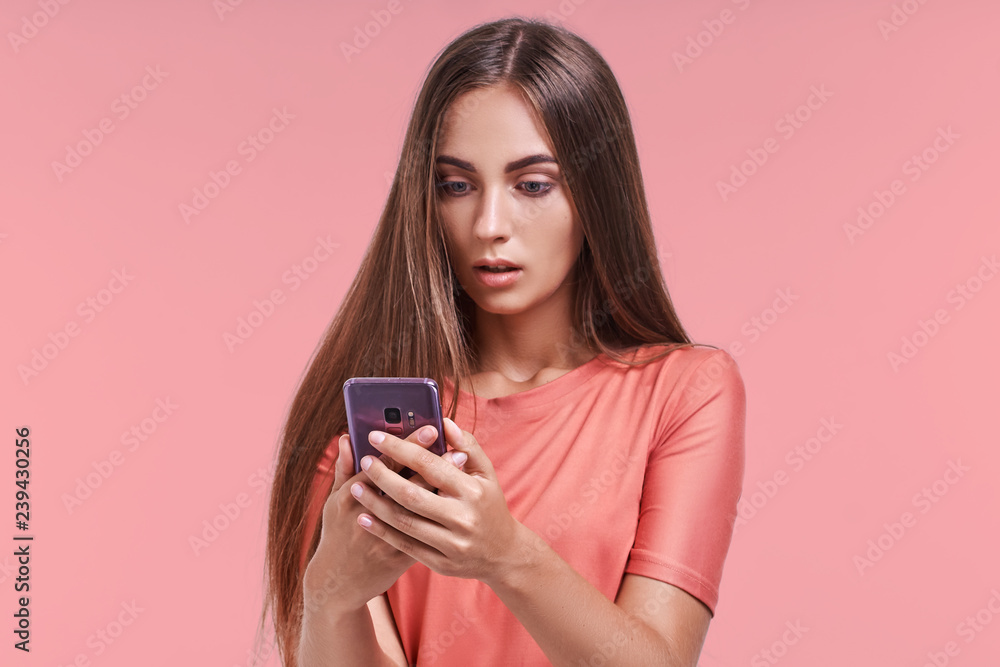Portrait of beautiful young female looks shocked in smart phone, sees calendar date, finds out that she can`t manage to go on meeting, types message of refusal. People, emotions and technology concept Portrait of beautiful young female looks shocked in smart phone, sees calendar date, finds out that she can`t manage to go on meeting, types message of refusal. People, emotions and technology concept