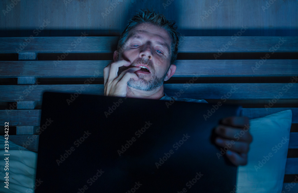 man alone in bed playing cybersex using laptop computer watching  