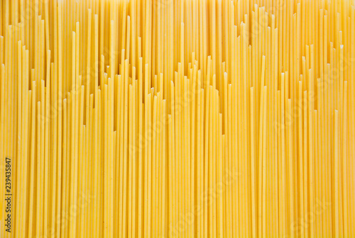 pile of yellow raw spaghetti, yellow pasta background ready for cooking, top view