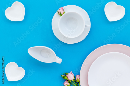 Empty white and pink colorful plate and rose for table setting on blue table backgroung top view