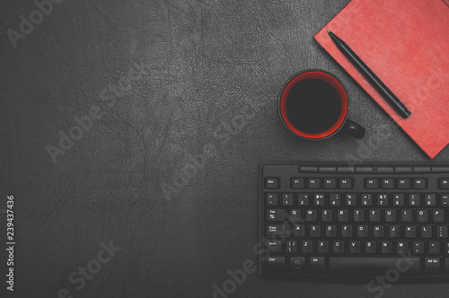 Keyboard, notebook, pen, cup of coffee on a black background. Black and red. Top view. Desktop