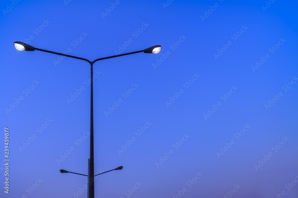 Feeling like eyes fixed and smile face background. Silhouette electric lamp poles with white lighting on beautiful clear blue sky in twilight time and copy space
