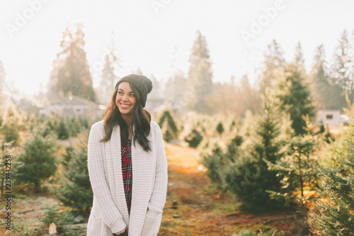A beautiful woman standing in a Christmas tree farm. 