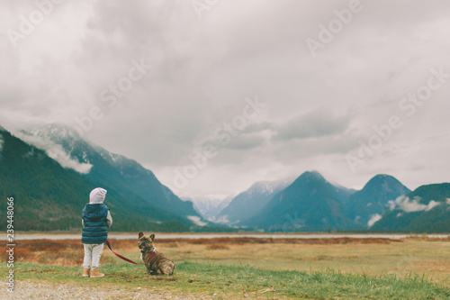 A little boy walking his dog in the mountains. 