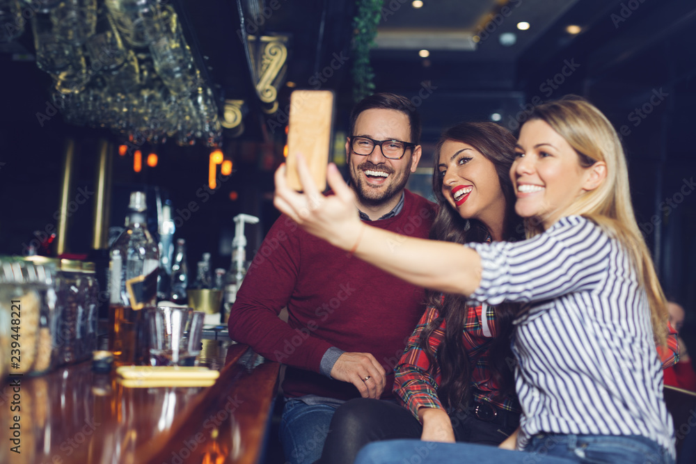 Three friends taking selfie in a bar.
