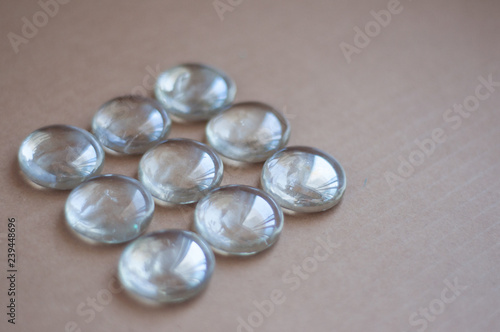Clear marbles with light reflections on a brown background.