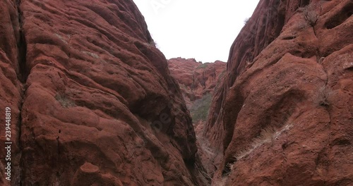 Moving shot, walking sideways between the red sandstone mountains, on a cloudy day, at Jeti-Oguz, in Kyrgyzstan photo