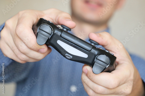 Joystick in male hands close-up, gamer playing video games with gamepad. Gaming addiction concept, home leisure