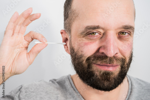 Man removing wax from ear using Q-tip