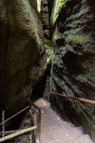 A stone staircase with a wooden railing between the rocks.