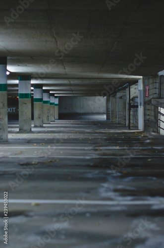 The long and empty salt covered parking stalls in the dark parking garage in the late night. 