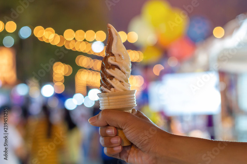 Ice cream cone on bokeh background. The woman holding the ice cream by hand.