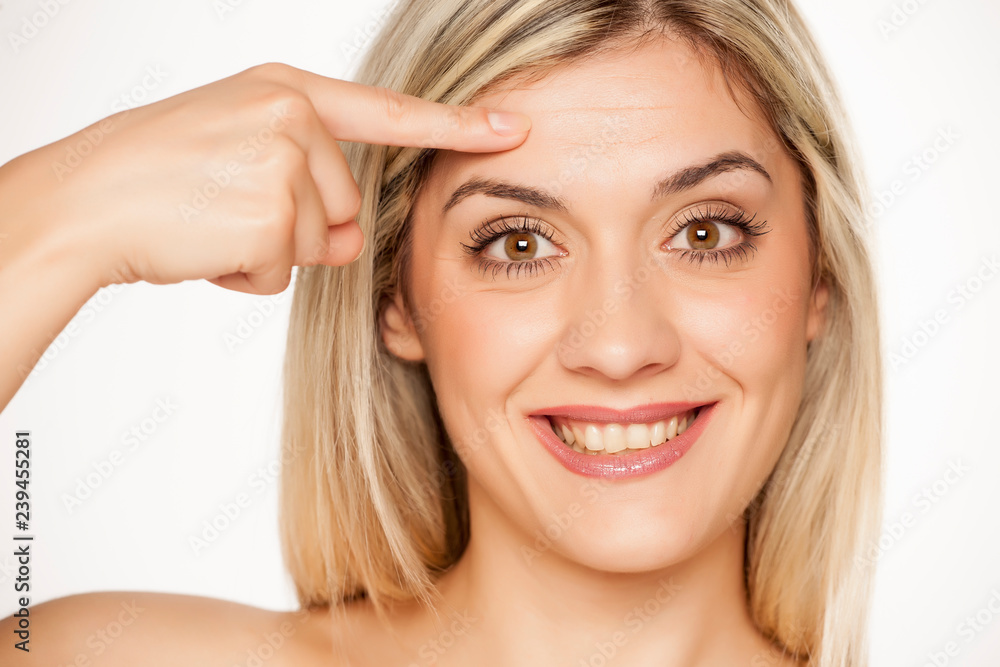Portrait of young blond woman, touching her forehead on white background Portrait of young blond woman, touching her forehead on white background