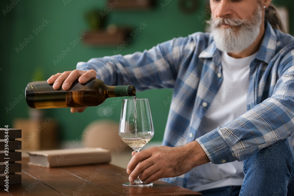 Senior man drinking wine at home