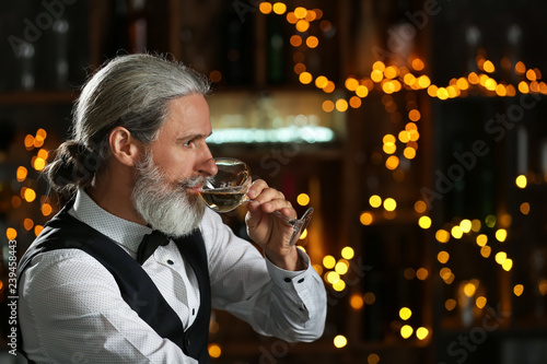 Senior man drinking wine in...