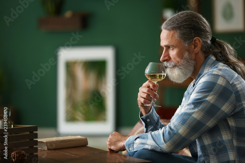 Senior man drinking wine at...