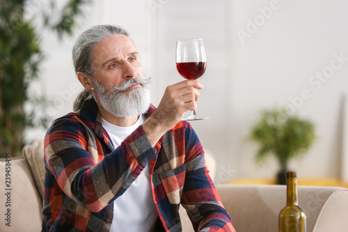 Senior man drinking wine at...
