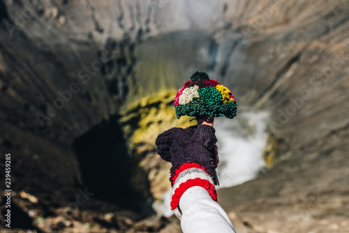 Hand holding flower bouquet for praying on volcanic mountain Bromo ,Indonesia photo