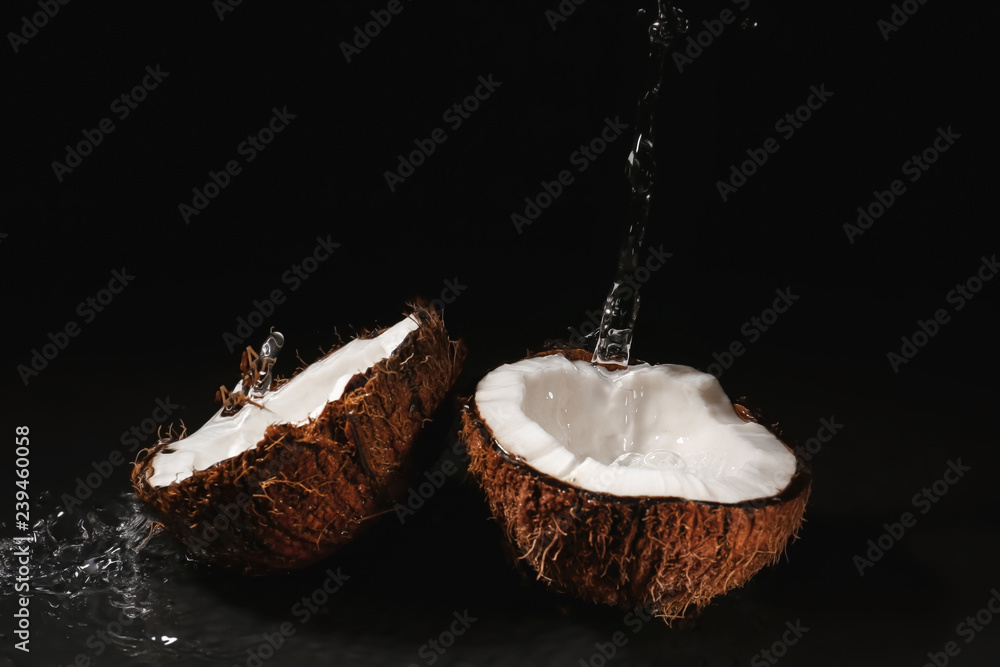 Ripe coconut and splash of water on dark background Ripe coconut and splash of water on dark background