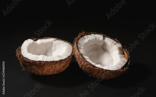 Halves of ripe coconut on dark background