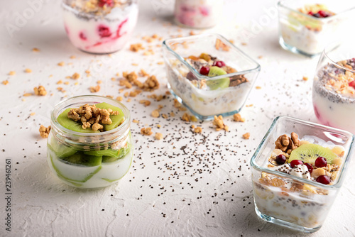 Tasty granola with yogurt and fruits on white table