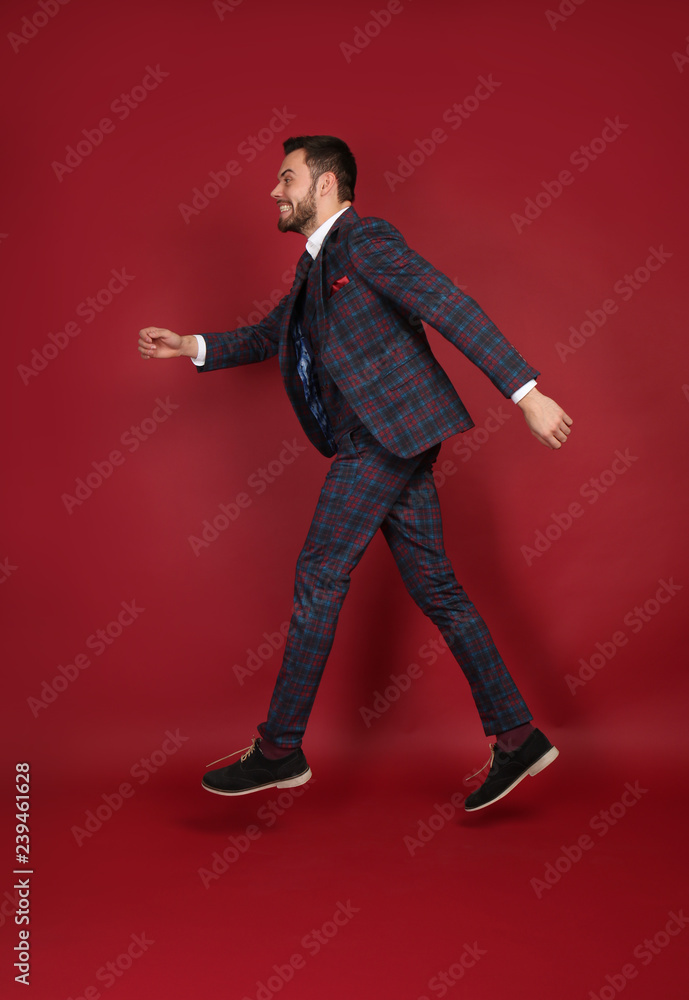 Jumping fashionable man in stylish suit on color background Jumping fashionable man in stylish suit on color background