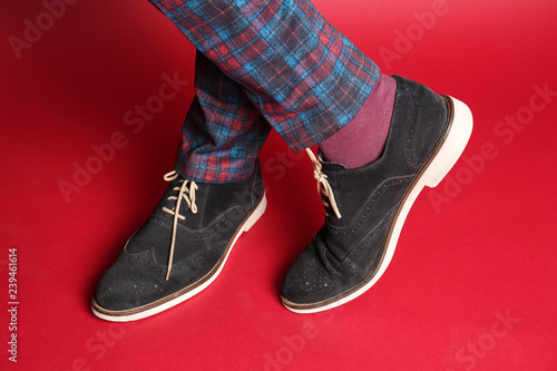 Young man in stylish shoes on color background, closeup
