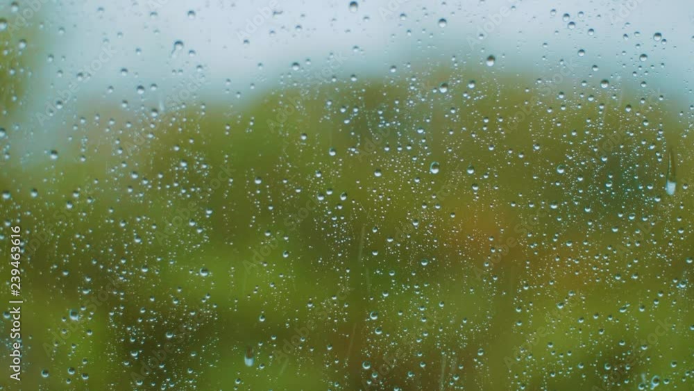 Close up shot of rain drops falling down a clear car window during a thundery rainstorm Close up shot of rain drops falling down a clear car window during a thundery rainstorm