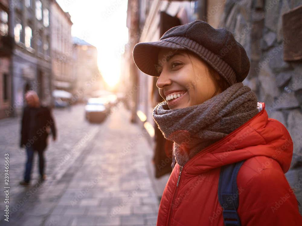 young woman in red jacket and gray cap walking on the street at evening young woman in red jacket and gray cap walking on the street at evening